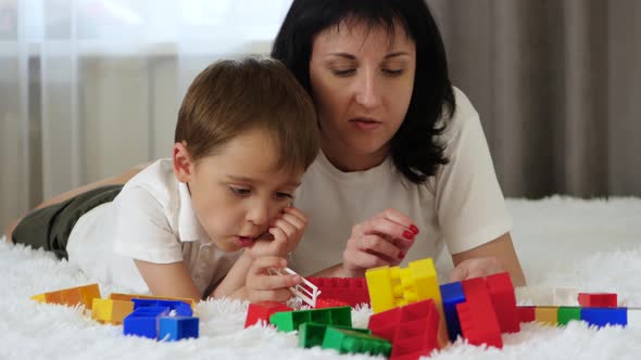 Happy Family Resting Lying on the Bed. Mother and Child Play, Building of Colored Blocks