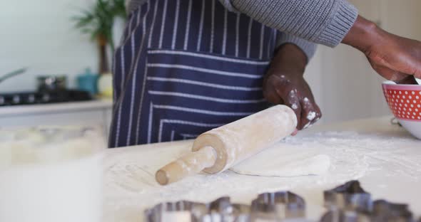 Hands of african american man using flour, preparing dough in kitchen