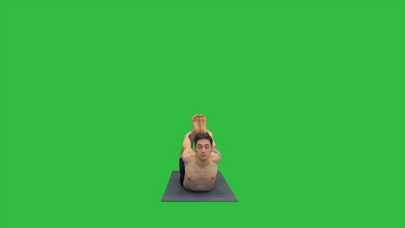 Shirtless athletic man demonstrates a yoga bow pose on