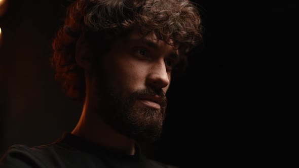 Closeup of Lowangle Shot of Bearded Young Man Having Online Video Call Via Laptop in Dark Room