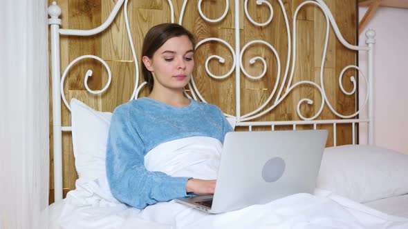 Wondering Woman in Bed in Shock By Results on Laptop