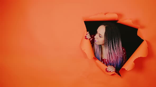 Bright Woman Looking Out of Hole of Orange Background
