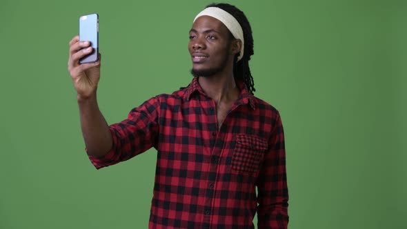 Young Handsome African Man with Dreadlocks Against Green Background