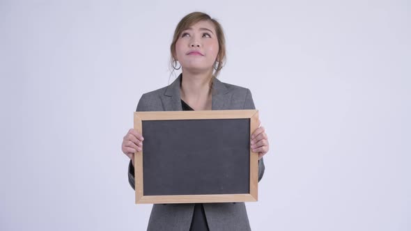 Young Happy Asian Businesswoman Thinking While Holding Blackboard