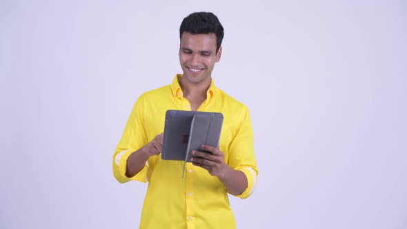 Happy Young Indian Businessman Thinking While Using Digital Tablet