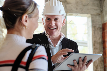 an working as realtor in construction site with customer. Real estate broker showing home to woman.