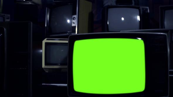 Retro TV Set Turning On Green Screen Among Many Vintage Televisions. Dolly Shot.