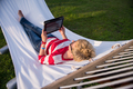 woman using a tablet computer while relaxing on hammock - PhotoDune Item for Sale