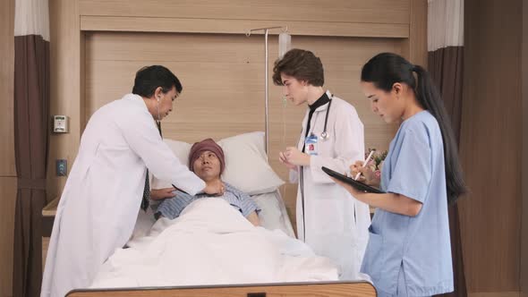 Doctors team health check a male patient in inpatient room bed of hospital ward.