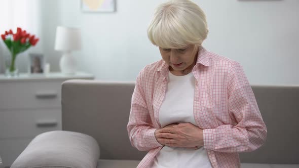 Upset Old Woman Holding Hands on Stomach, Suffering From Gastritis Disease