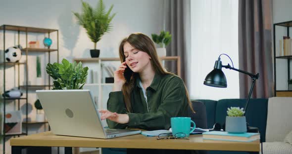 Smart Girl Working on Computer in Home Office and Talking on Mobile simultaneously