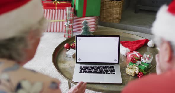 Caucasian senior couple in santa hats on video call on laptop with copy space at christmas time