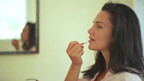 Closeup of a Caucasian Girl Painting Her Lips at Home in an Apartment