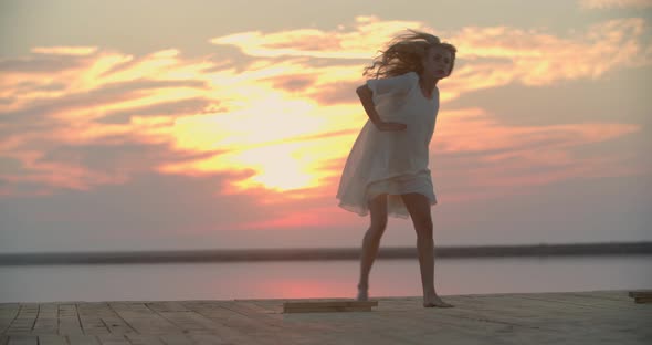 Pier of the Lake with a Young Blonde Woman Dancing During Sunset