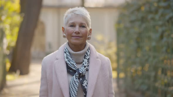 Portrait of Aged Female in Fashionable Outfit Looking at Camera Outdoors