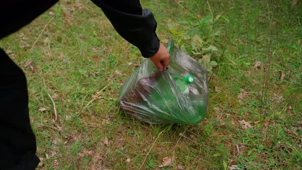 Unrecognizable person take bag trash at meadow forest. Plastic waste bag on grass at nature