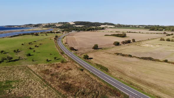 Aerial view of the coastline of Sejerøbugten with Vejrhøj, road, fields and ocean.