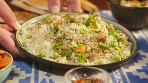 Putting Cooked Couscous with Chicken on Table Closeup
