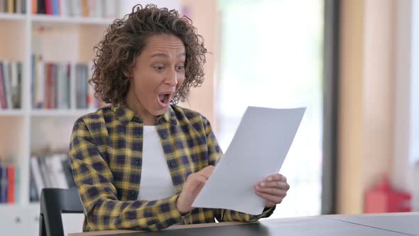 Excited Mixed Race Woman Celebrating Success on Documents