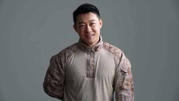 Cheerful soldier Asian man holds out a bouquet of red roses to the camera