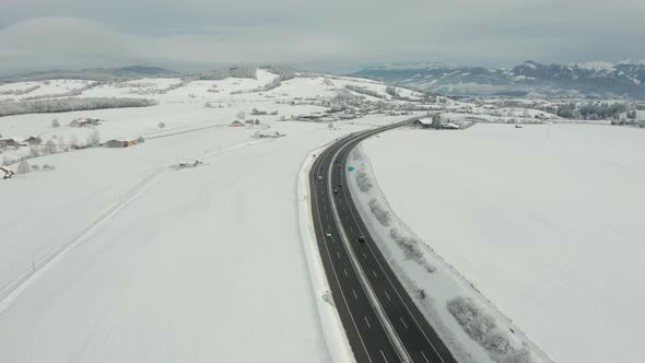 Aerial of busy highway running through snow covered rural landscape