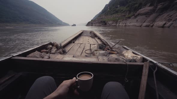 Crop man with coffee sitting in boat
