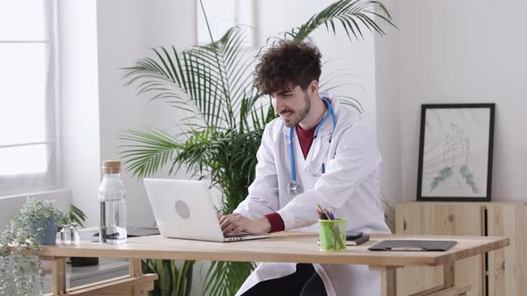 Young Man Doctor Working on Personal Laptop at His Medical Office