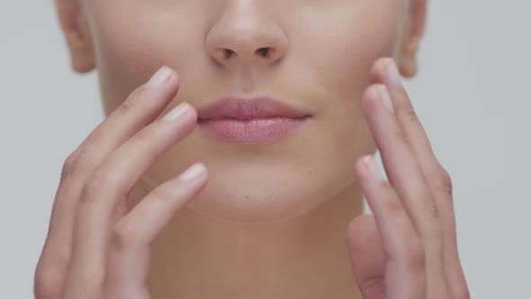 Studio portrait of young, beautiful and natural blond woman applying skin care cream. F