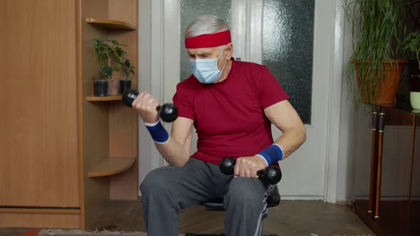 Senior Elderly Caucasian Man Making Weight Lifting Dumbbells Exercising at Home During Coronavirus