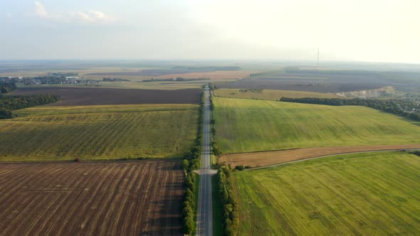 A Landscape of Plowed Land and Green Fields on Both Sides of a Highspeed Road