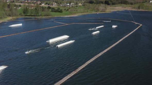 Wakesurfers Riding Waterski Cable Wake Park on Sunny Day