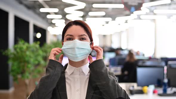 Joyful Woman in a Suit Takes Off a Medical Mask in the Office