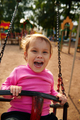 Little girl with funny facial expression swinging on the swings - PhotoDune Item for Sale