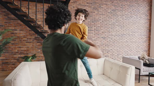 Biracial Boy Dances on Sofa Having Fun with Elder Brother