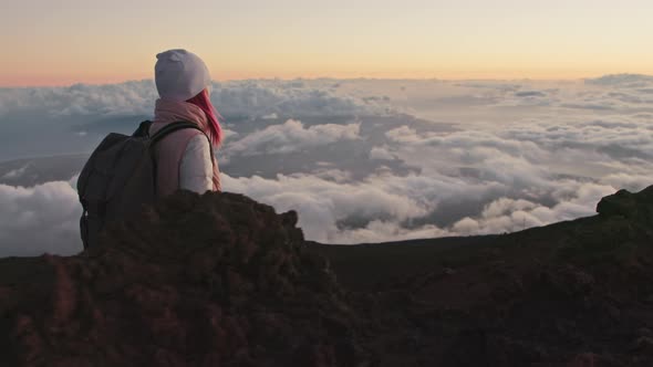 Cinematic Cloudscape at Sunset Woman with Backpack Hiking Volcanic Mountain