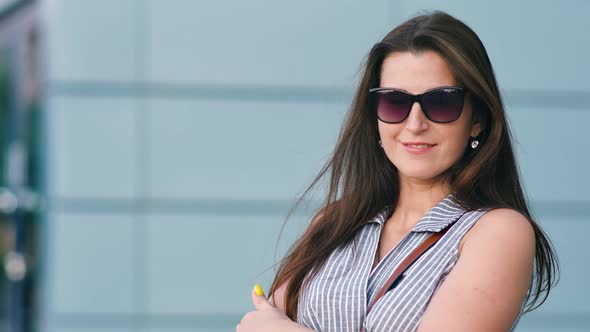 Attractive Woman Standing in Front of Modern Wall of Office Building with Arms Crossed