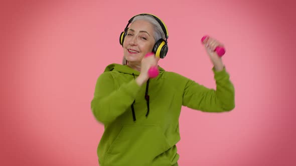 Senior Granny Woman Listening Music Via Headphones Working Out Lifting Pink Dumbbells Healthcare