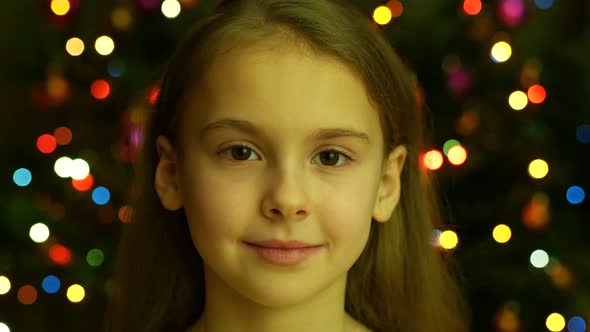 Close Up View Preteen Girl Looking Into the Camera on the Background of Garland Lights