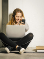 Young woman laughing at her smartphone - PhotoDune Item for Sale