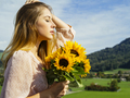 Young woman enjoying the sunlight holding sunflowers - PhotoDune Item for Sale