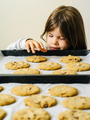 Young girl grabbing cookies from a baking tray - PhotoDune Item for Sale
