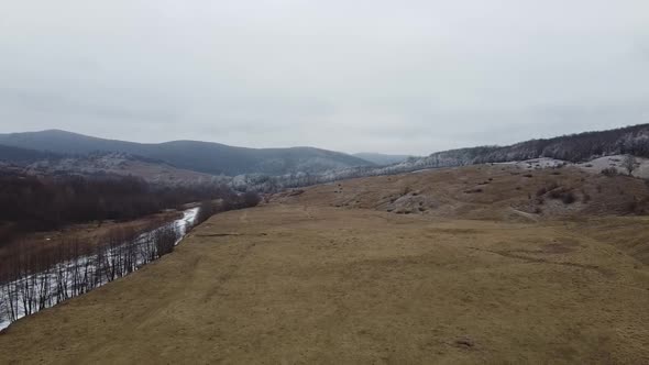 Drone shot of the forest and a country icy river in the late autumn. Late Autumn forest hills. Aeria