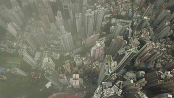 Tilt up aerial view of Hong Kong city skyline through the clouds revealing the harbour