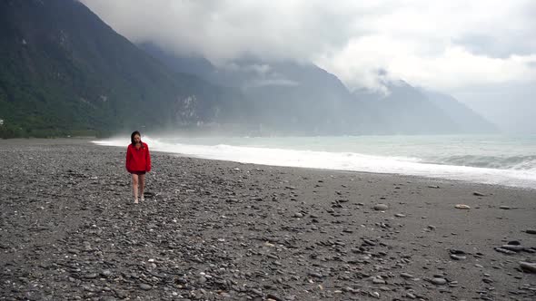 Asian woman walking on rocky beach