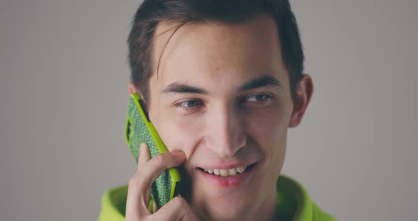 Closeup Smiling Young Handsome Man Speaking Phone Emotionally at Grey Wall Background