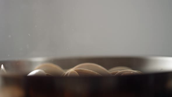 Camera follows adding pasta on cooked clams in a pan. Slow Motion.