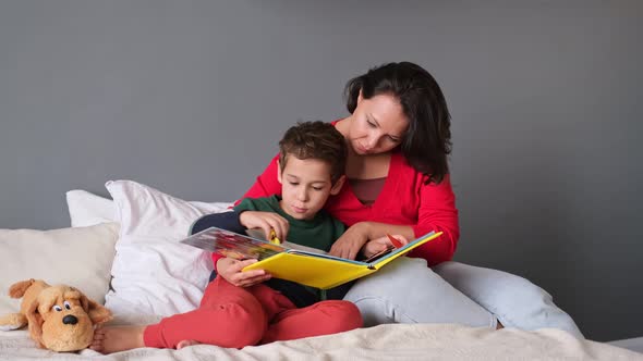 Mother and Son Reading Book Together on Bed