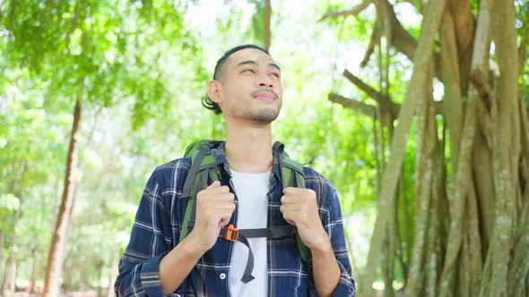 Asian young handsome male backpacker traveling alone in forest wild.