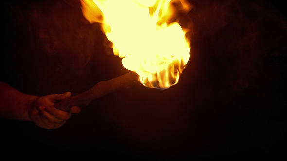 Person Holds Up Burning Torch In The Dark