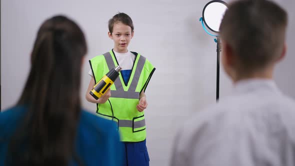 Confident Little Repairman Explaining Power Drill Use for Friends Talking at White Background